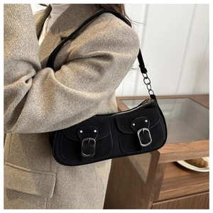 Detail of black suede shoulder bag featuring double front pockets and silver metal buckles