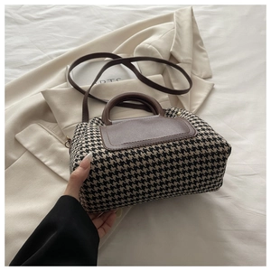 Detail of vintage houndstooth handbag with brown leather trim and retro trapezoid shape