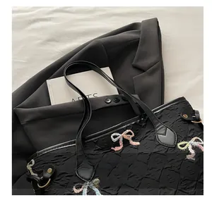 Detail of black tote bag with textured fabric and colorful embroidered butterfly bows