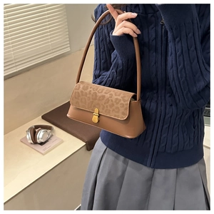 Brown underarm bag with leopard print flap and gold lock shown in a lifestyle setting