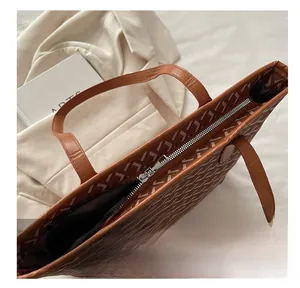 Detailed close-up of smooth silver zipper on a brown tote bag with chevron pattern