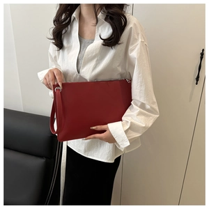 Detail of red leather envelope clutch bag with wrist strap and silver metal zipper