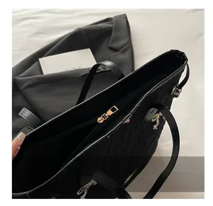 Close-up of smooth metal zipper and quilted texture on black tote shoulder bag