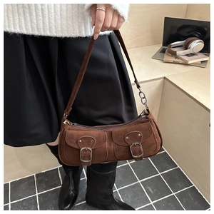 Close-up of brown suede shoulder bag with dual buckle pockets and metal chain strap