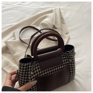 Detail of vintage houndstooth handbag with brown leather accents and gold hardware