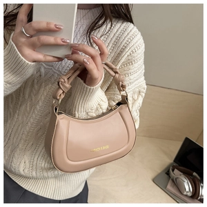Detail of minimalist beige leather shoulder bag with trendy knotted handle and printed text