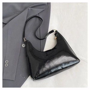 Glossy black hobo shoulder bag shown on a gray blazer for an elegant fashion style