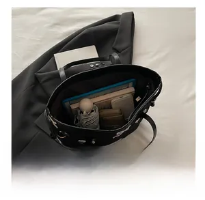 Detail view of spacious black tote bag interior holding tablet, umbrella, and essentials
