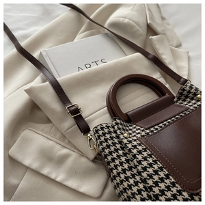 Detail of vintage houndstooth handbag with brown leather trim and gold hardware