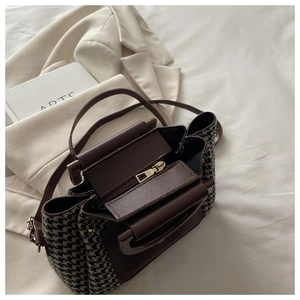 Detail of vintage houndstooth handbag with brown leather trim and metallic zipper closure