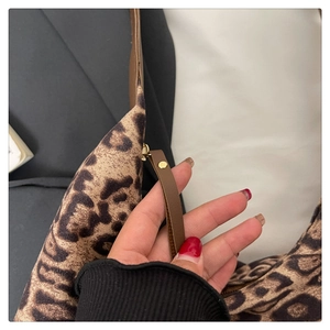 Détail du sac cabas léopard avec bandoulière en cuir marron et rivets dorés en métal