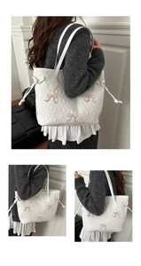 Close-up of quilted white tote bag featuring colorful embroidered bows and drawstring