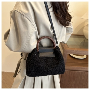 Detail of plush black shearling handbag with vintage round wooden handles and shoulder strap