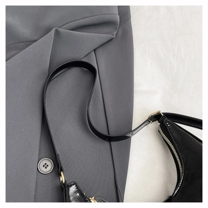 Detailed macro view of black glossy shoulder bag showing premium hardware and zipper