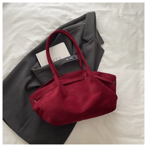 Detail view of burgundy suede tote bag with dual straps on aesthetic white background