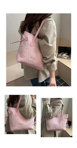 Detail of light pink pleated shoulder bag featuring delicate blue bow embroidery accents