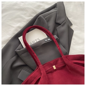 Close-up of a dark red suede tote bag featuring premium golden metal buckle details