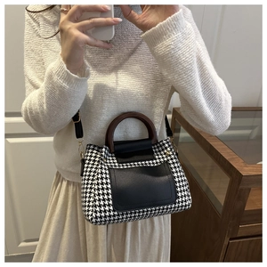 Detail of retro houndstooth tote bag featuring unique brown wooden circular handles