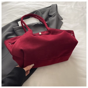 Detail of burgundy suede tote bag featuring sleek golden magnetic metal clasp closure