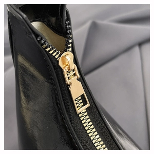 Detailed macro view of the premium golden metal zipper on a black leather handbag