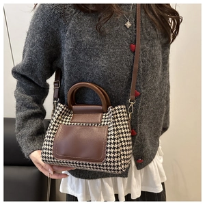 Detail of houndstooth wool fabric texture and brown leather strap on vintage crossbody bag