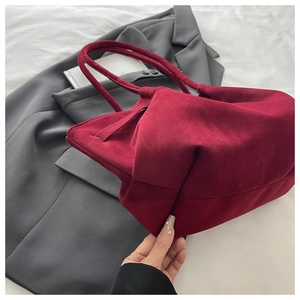 Detail of trendy burgundy velvet handbag placed on a grey blazer for fashion display