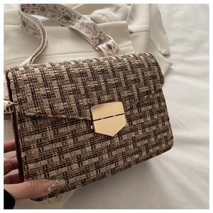 Gros plan du sac bandoulière en tweed tissé avec fermoir doré et sangle brodée