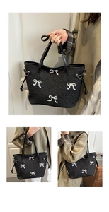 Detail of black tote bag featuring textured fabric and beaded bow-knot patches