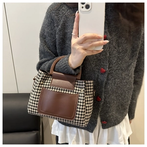 Detail of retro houndstooth tote bag with brown faux leather trim and sturdy top handle
