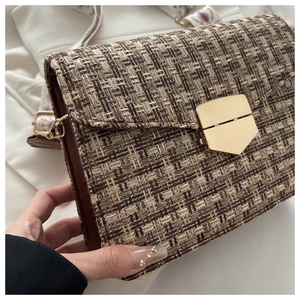 Détail du sac tissé avec fermoir doré géométrique et bandoulière brodée