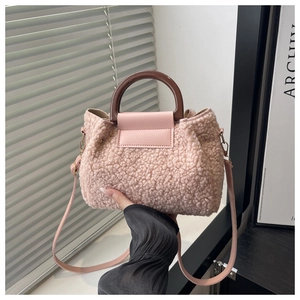 Pink shearling crossbody bag with dark wooden handle and leather strap detail