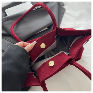 Detail of burgundy velvet tote bag featuring dual magnetic metal clasps and grey lining