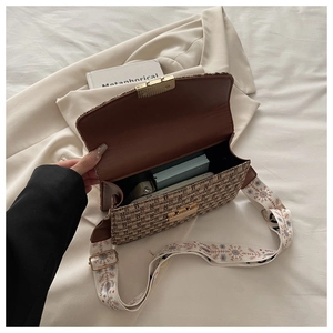 Détail du sac bandoulière en tweed tissé avec boucle dorée et large sangle brodée