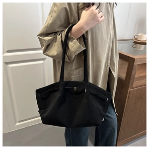 Close-up of black tote bag featuring a silver metal buckle and classic shoulder strap