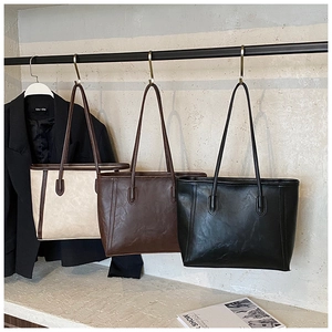 Détail de trois grands sacs cabas en cuir PU déclinés en crème, marron et noir classique