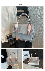 Silver glitter crossbody bag with decorative silk scarf handle showing hand-held detail
