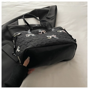 Détail du sac à bandoulière noir plissé avec broderies de nœuds colorés sur tissu