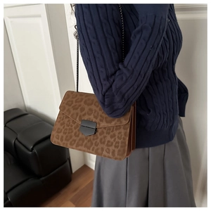 Gros plan du sac bandoulière léopard avec chaîne porté sur une tenue d'automne chic