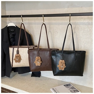 Trois sacs cabas minimalistes en beige, marron et noir avec des breloques d'ours