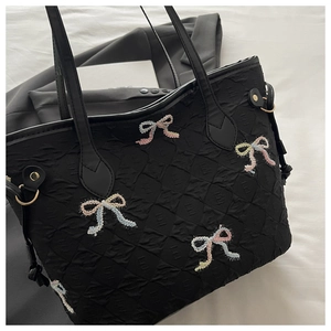 Détail du sac cabas noir à texture quadrillée avec broderies nœuds et fines bretelles