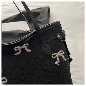 Détail du sac à bandoulière en tissu matelassé avec nœud brodé et anse en cuir