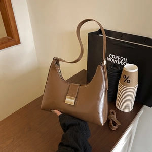 Brown leather crescent hobo bag with gold hardware shown in a stylish urban setting