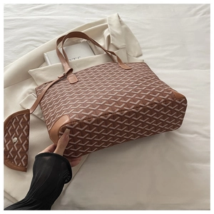 Detail of Goyardine style tote bag set with signature pattern and brown leather trim
