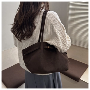 Detail of dark brown suede tote bag with slim shoulder strap and leather buckle side