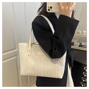 Detailed shot of white corduroy tote bag with slim faux leather straps and brand patch
