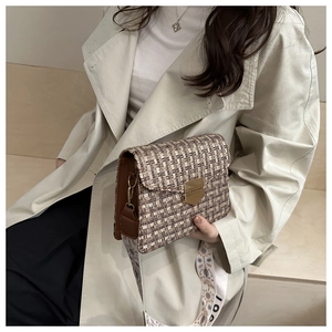 Gros plan d'un sac sous les bras en tweed avec boucle dorée et bandoulière tissée