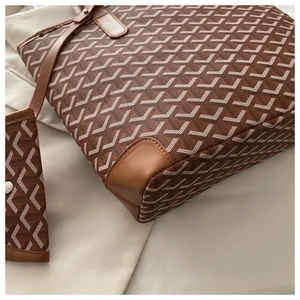 Close-up of brown tote bag with white Y-pattern print and matching pouch on soft fabric
