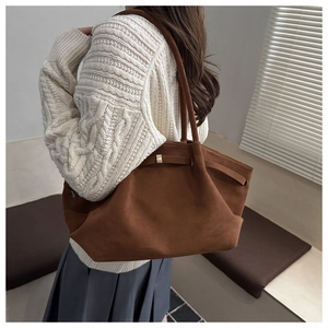 Detail of a brown suede tote bag featuring pleated design and gold metal buckle accents