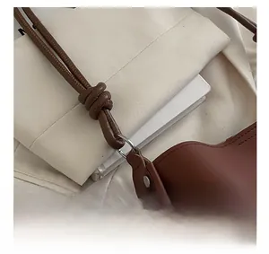 Detail showing silver metal D-rings and rivets on a brown leather shoulder bag