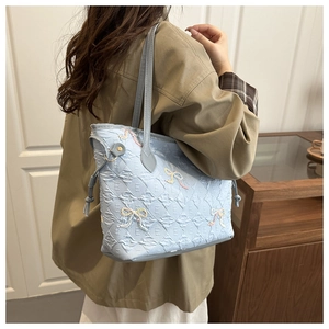 Detail of light blue tote bag with 3D letter texture and colorful bow embroidery charms